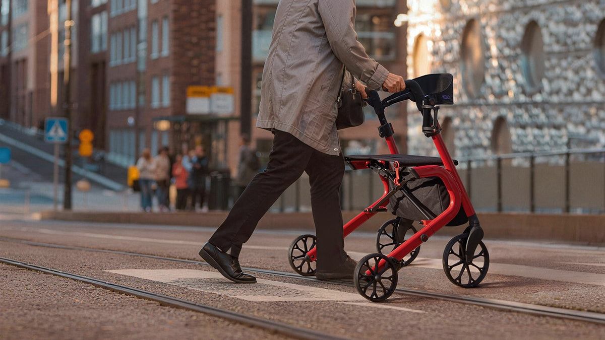 Person using a red kekoy rollator on a city street 