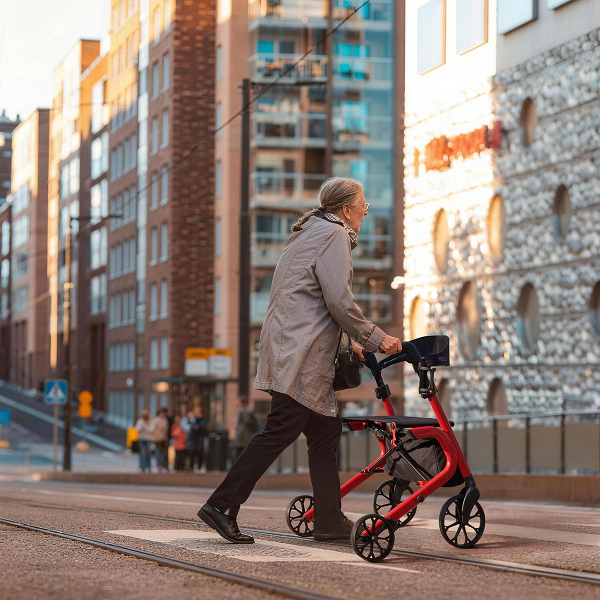 Person pushing a red kekoy rollator on a city street