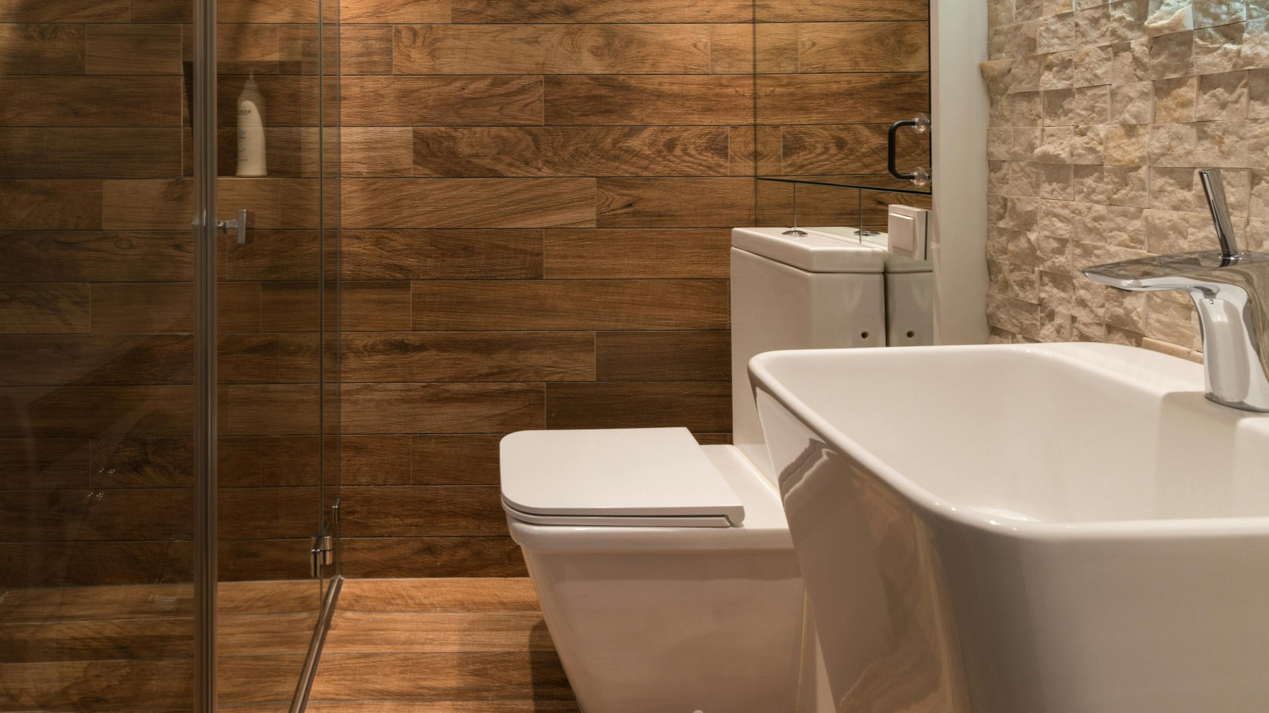 Modern bathroom with wooden walls, toilet, and bathtub.