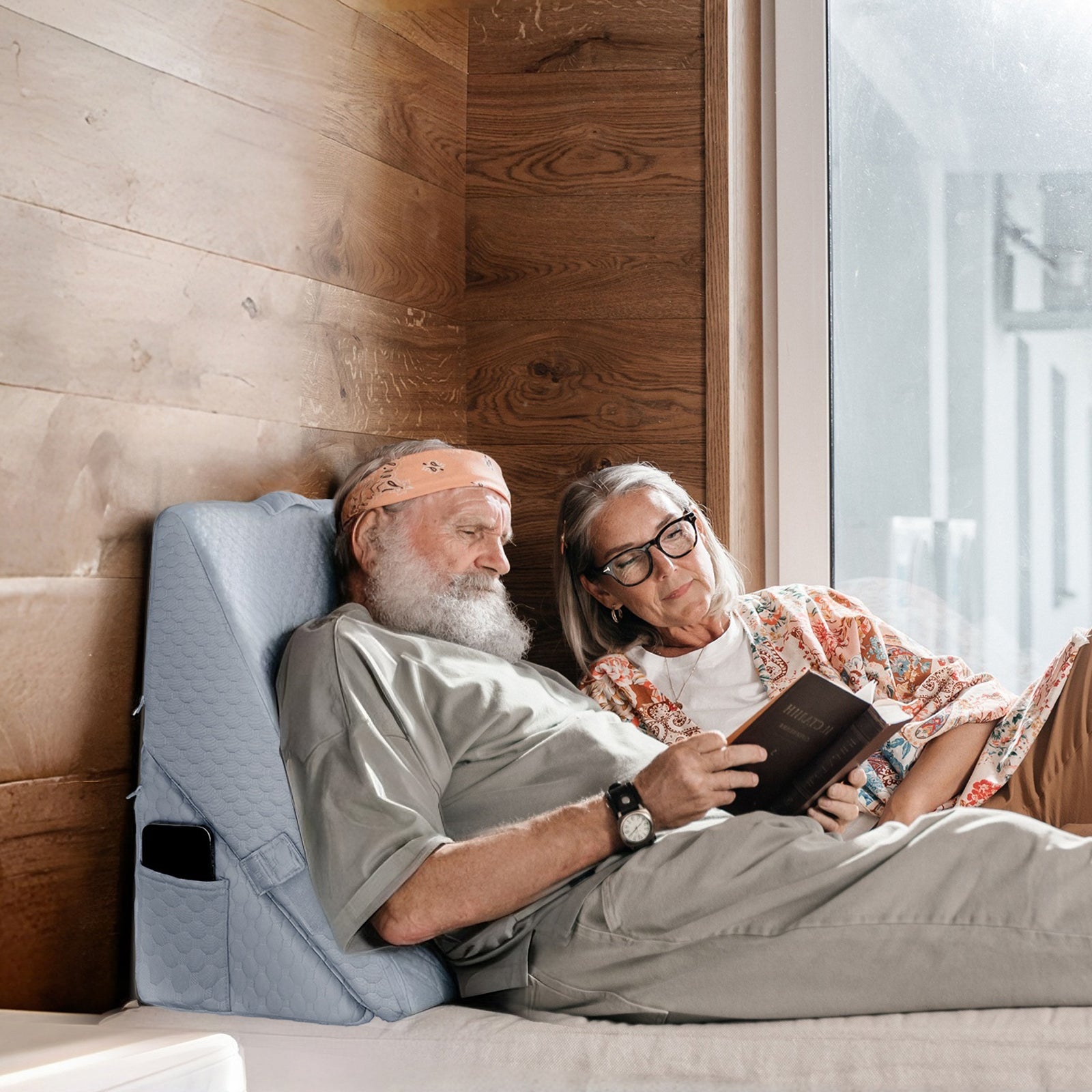An elderly couple read a book while using kekoy wedge pillow for back support