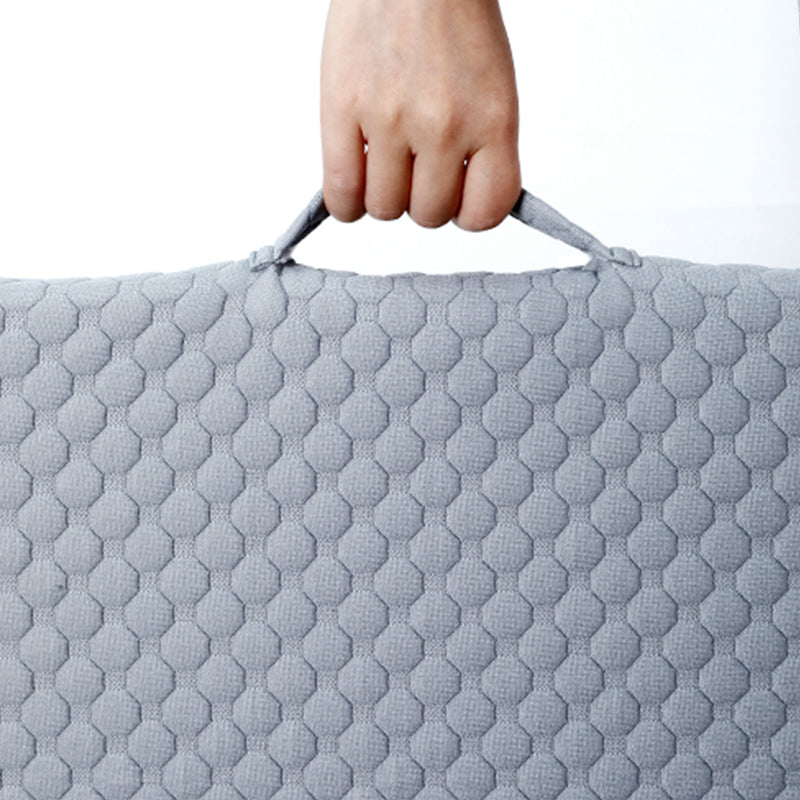 A close-up of a light gray wedge pillow with handle