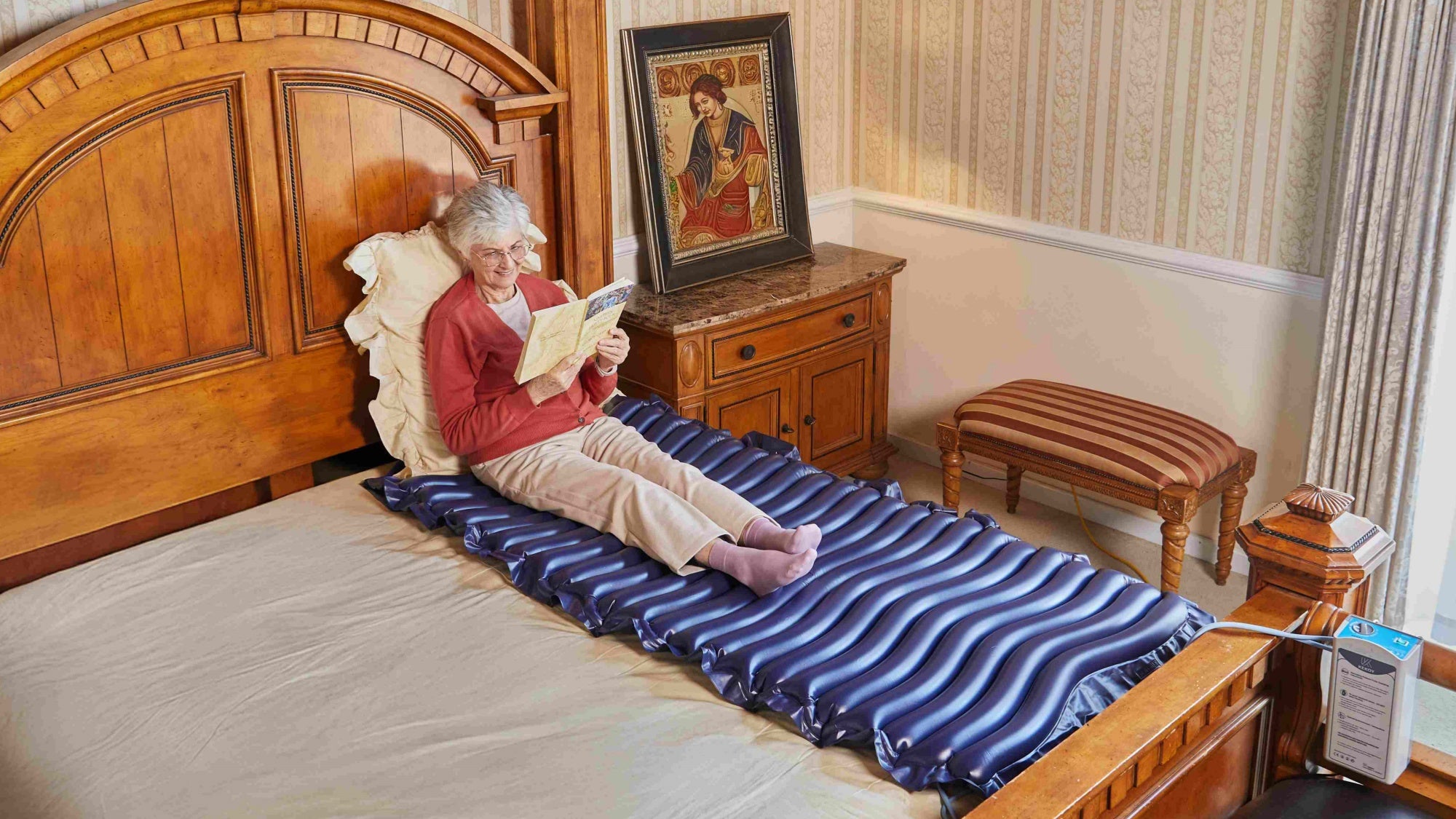 Woman sitting on kekoy air mattress in a bedroom reading a book.