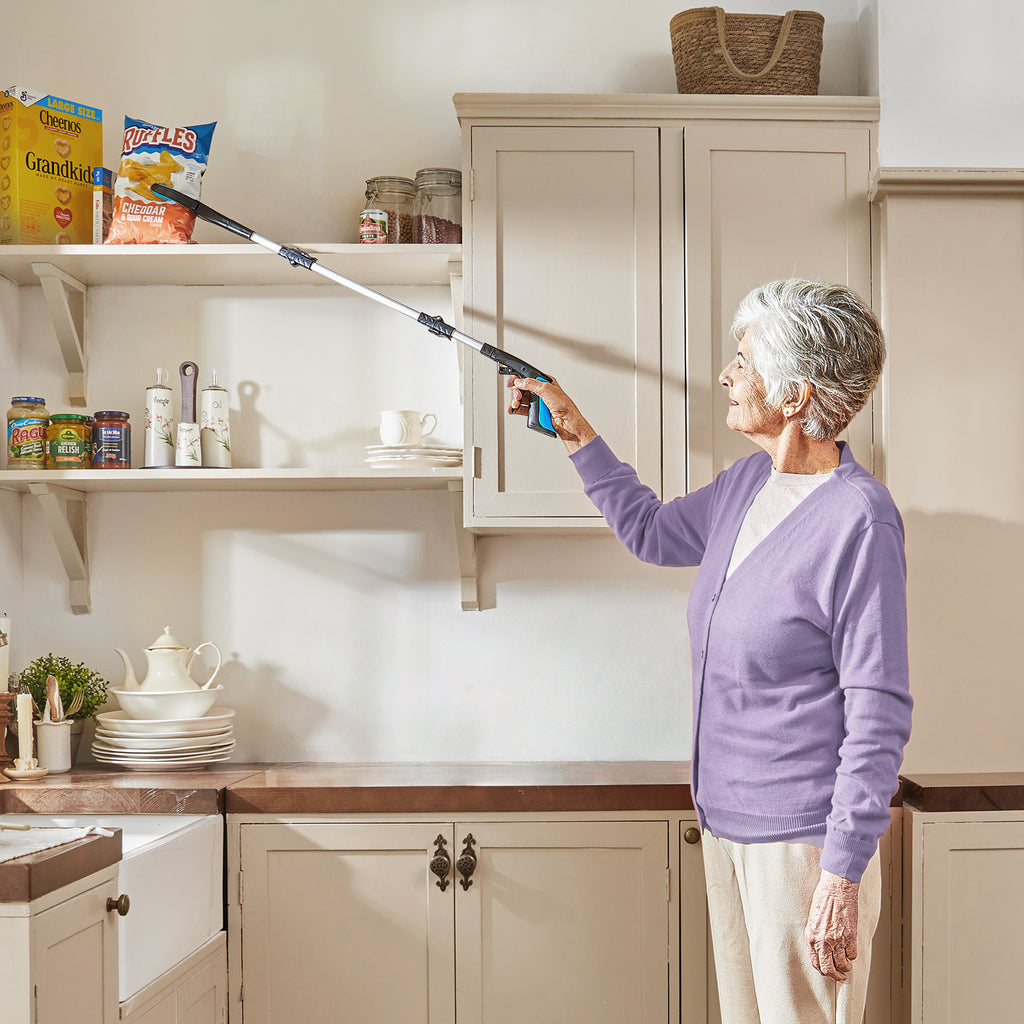 Woman using a grabber tool to reach high shelves in a kitchen