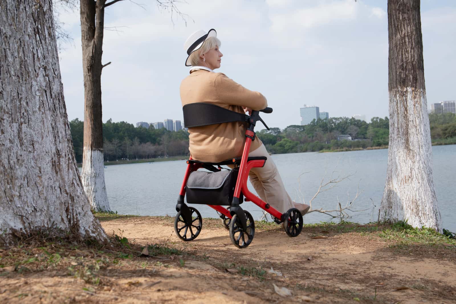 Woman using a red kekoy mobility rollator by a lake