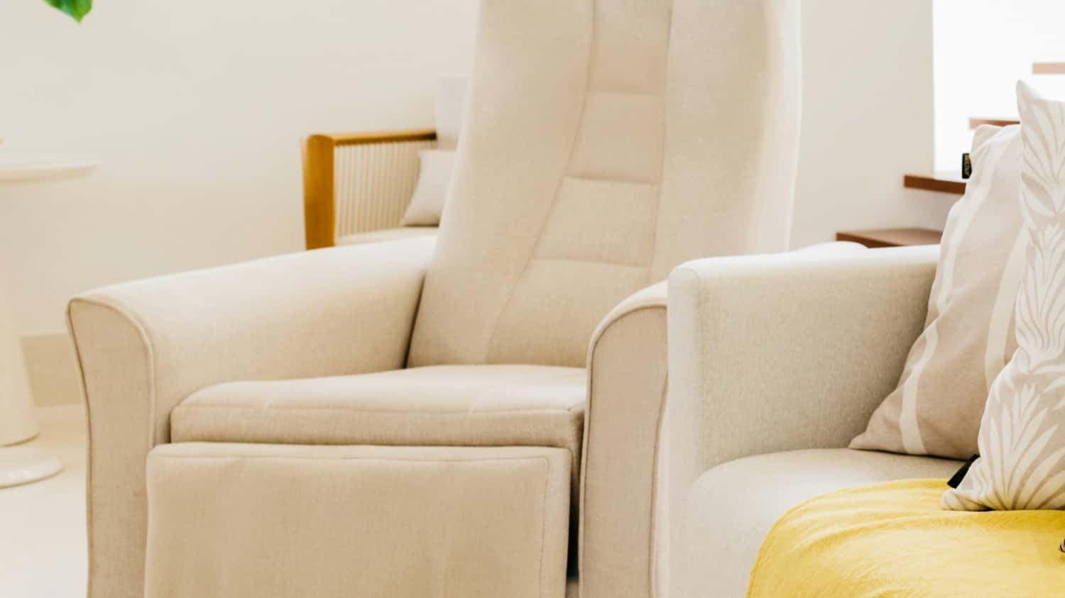 A cream-colored upholstered recliner chair with a high back